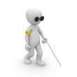 White cartoon figure walking using a white cane and wearing dark sunglasses.